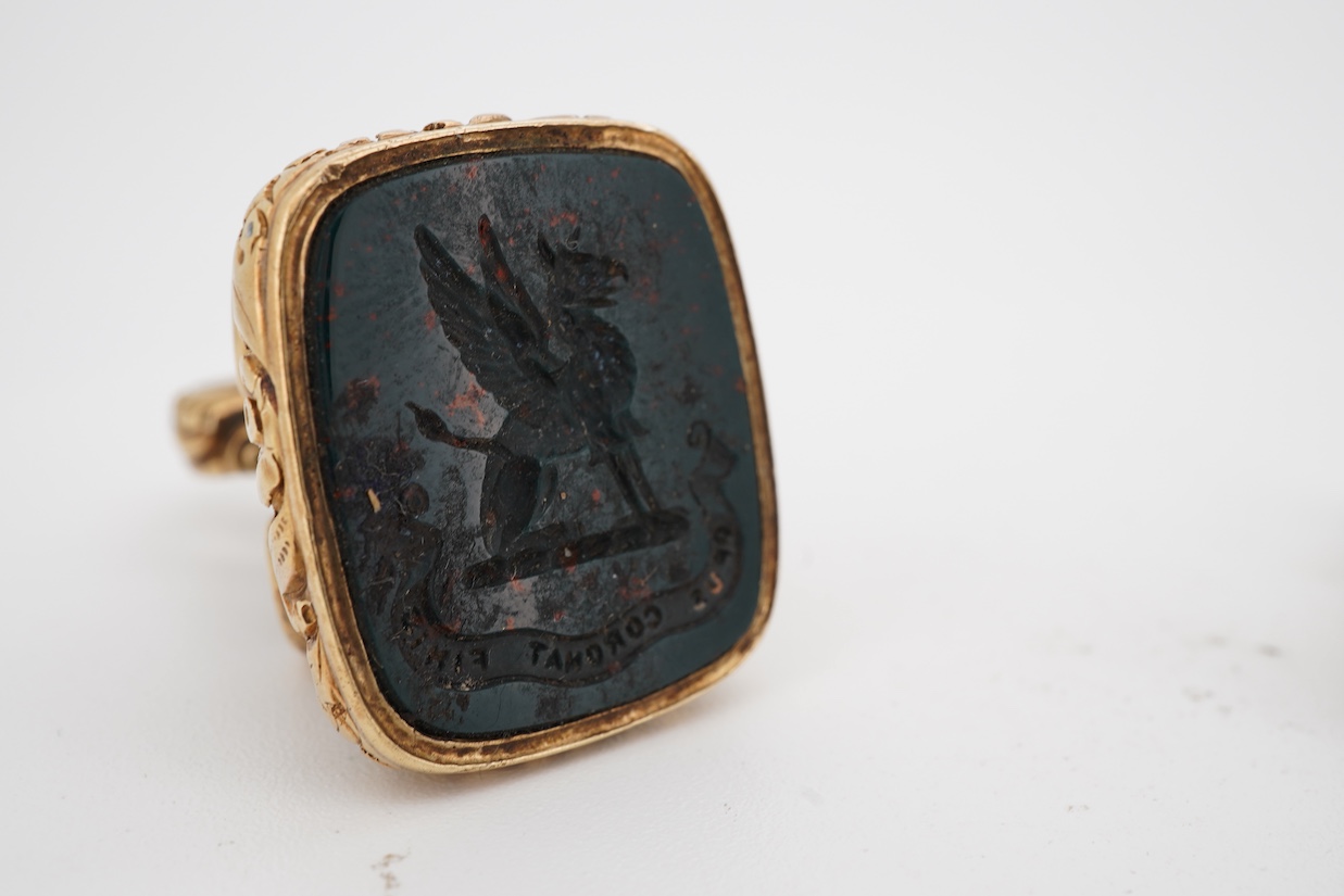 A 19th century yellow metal overlaid and bloodstone set fob seal, the matrix carved with a griffin and motto 'Opus Coronat Finis', 30mm, together with a similar gold plated fob seal and foil backed quartz fob seal, the m
